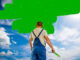Ein Mann streicht eine Wand vor einem blauen Himmel grün an