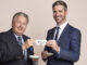 Zwei Männer stoßen mit Kaffeetassen an
