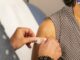 Ein Arzt klebt ein Pflaster auf die Impf-Einstichstelle