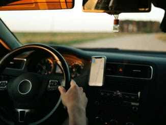 Zu sehen ist eine Person, die Auto fährt. Man sieht den Innerazm, Lenkrad sowie das Armaturenbrett.