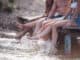 Cropped image of happy friends splashing water while sitting on pier at the sea