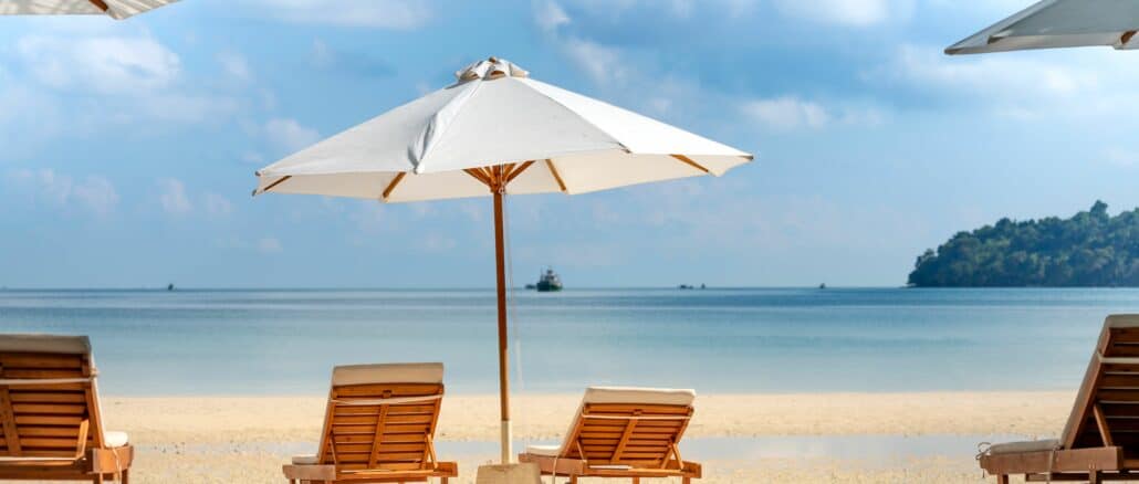 4 Liegestühle mit Sonnenschirm an einem Strand