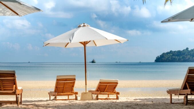4 Liegestühle mit Sonnenschirm an einem Strand